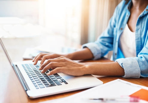 Shot of an unrecognizable young woman working on her laptop at home
